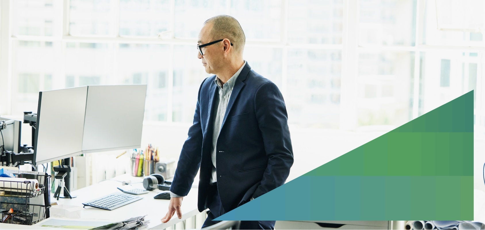 Businessman looks at a pair of computer monitors at his office work desk