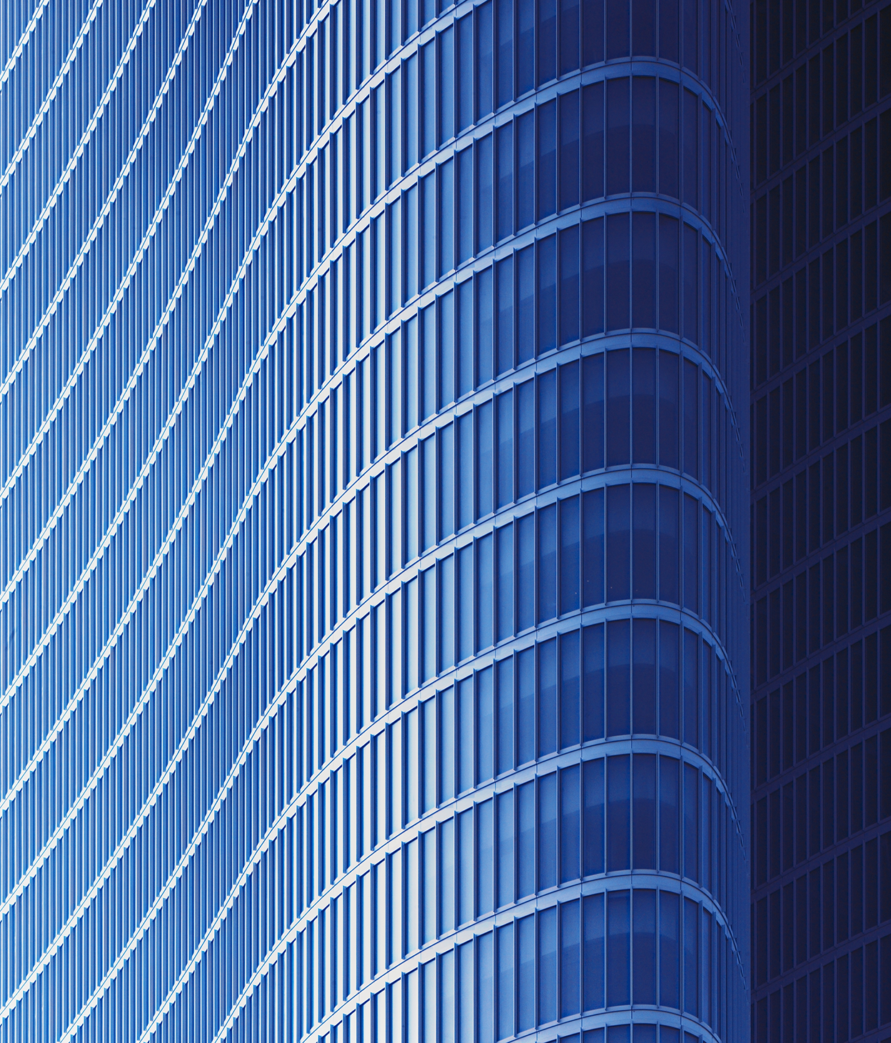 Photo en gros plan d’une façade incurvée d’un immeuble de bureaux en verre.